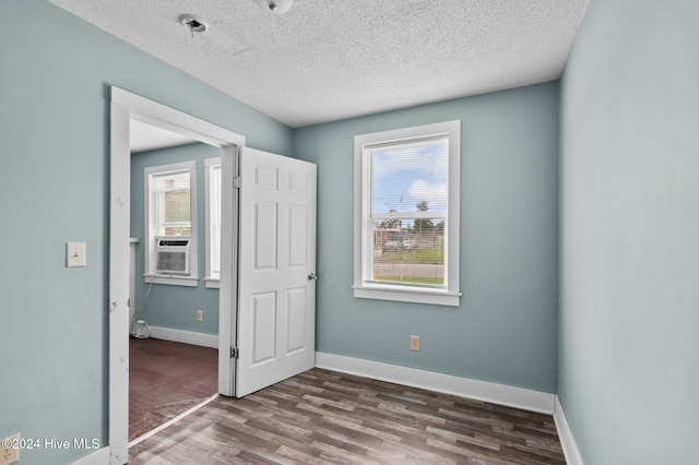 unfurnished bedroom featuring a textured ceiling, dark hardwood / wood-style floors, and cooling unit