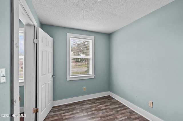 unfurnished bedroom with a textured ceiling, dark wood-type flooring, and baseboards