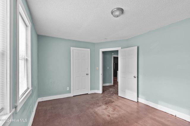 unfurnished bedroom featuring multiple windows, baseboards, and a textured ceiling