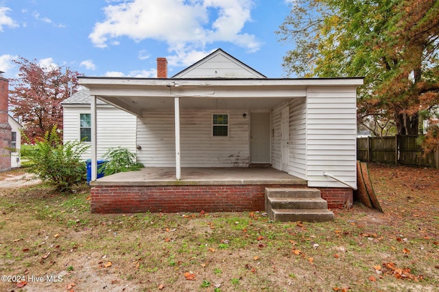 rear view of house featuring a patio area, fence, and a chimney