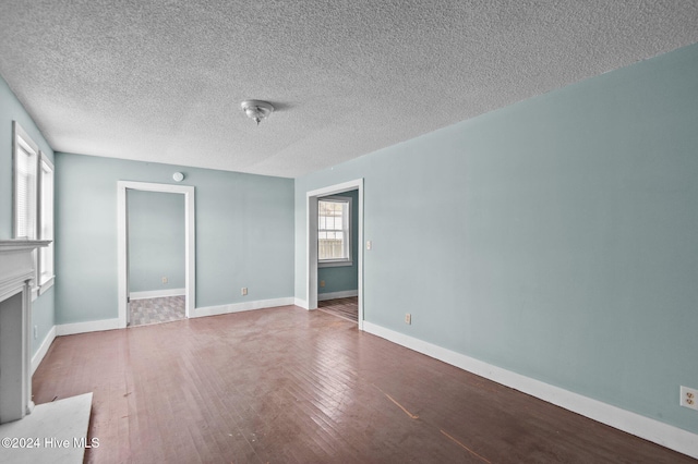 unfurnished living room featuring baseboards, a textured ceiling, hardwood / wood-style floors, and a fireplace