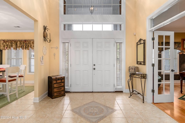 tiled entrance foyer featuring a high ceiling and crown molding