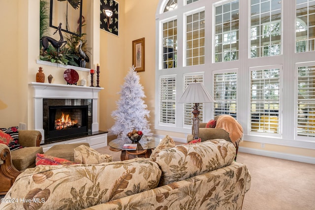 living area featuring a wealth of natural light, light carpet, and a towering ceiling