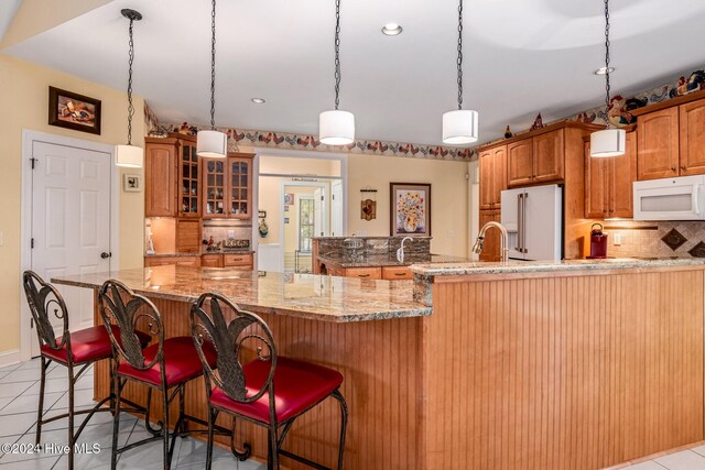 202 Jones Byrd Ct, Sunset Beach, NC 28468 - kitchen with white appliances, backsplash, glass insert cabinets, a breakfast bar area, and light stone countertops