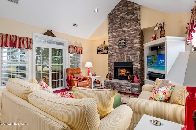 living room with a stone fireplace and high vaulted ceiling