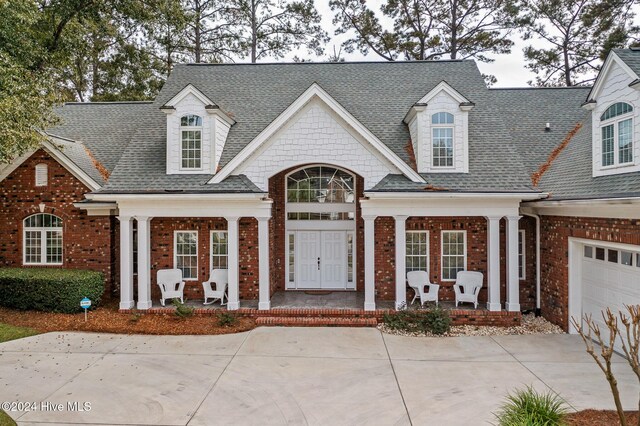 202 Jones Byrd Ct, Sunset Beach, NC 28468 - view of front of home featuring covered porch, brick siding, a shingled roof, and concrete driveway