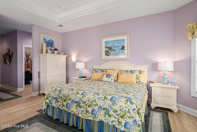 202 Jones Byrd Ct, Sunset Beach, NC 28468 - bedroom with wood finished floors, baseboards, crown molding, a tray ceiling, and a spacious closet