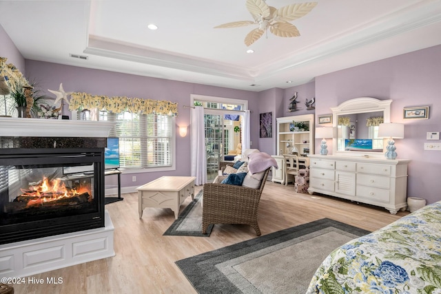 202 Jones Byrd Ct, Sunset Beach, NC 28468 - bedroom with a tray ceiling, light wood-style floors, a multi sided fireplace, a ceiling fan, and recessed lighting