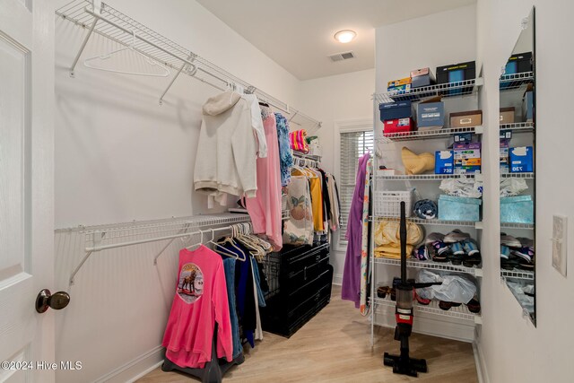 walk in closet with light hardwood / wood-style floors