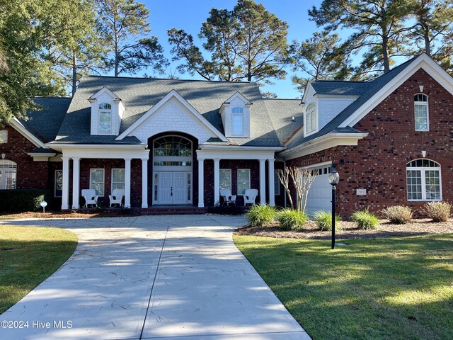 202 Jones Byrd Ct, Sunset Beach, NC 28468 - view of front of property with brick siding, concrete driveway, a front lawn, and a shingled roof
