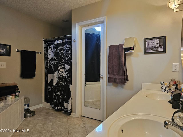 full bathroom with a textured ceiling, double vanity, a sink, and tile patterned floors