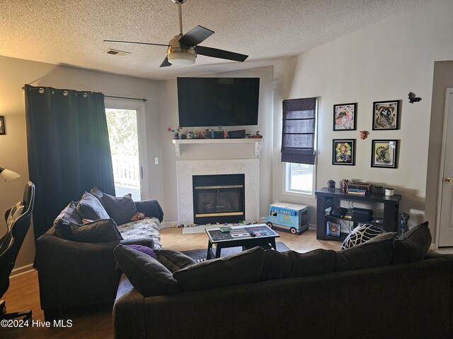 living room with ceiling fan, light hardwood / wood-style floors, and a textured ceiling