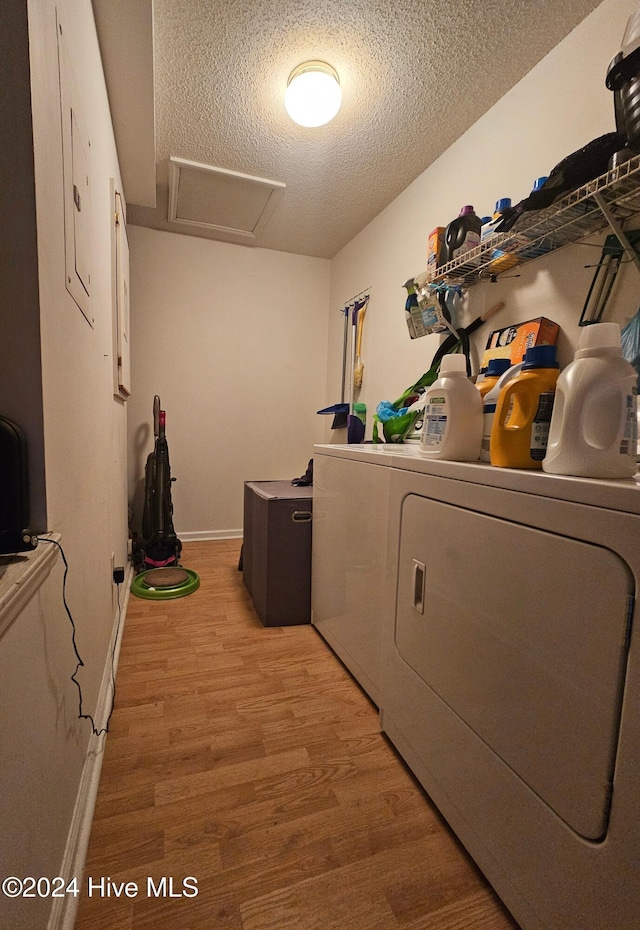 laundry area featuring laundry area, attic access, washer and clothes dryer, a textured ceiling, and light wood-style floors