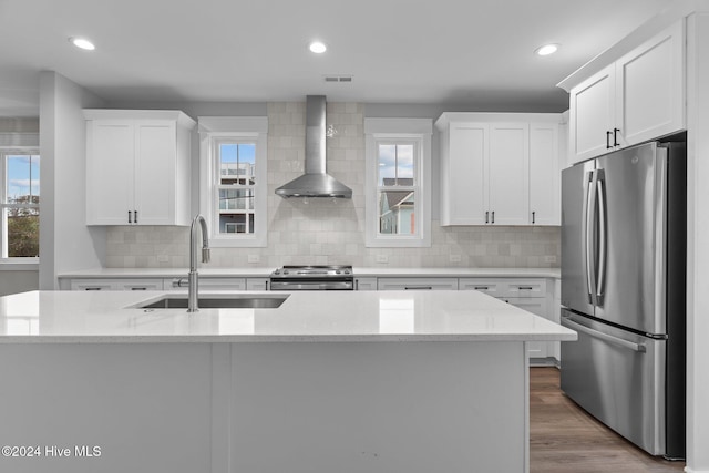 kitchen with stainless steel appliances, visible vents, white cabinetry, a sink, and wall chimney exhaust hood