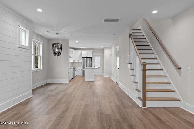 unfurnished living room featuring recessed lighting, visible vents, stairway, light wood-type flooring, and baseboards