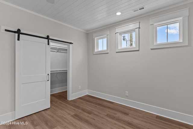 unfurnished bedroom featuring visible vents, a barn door, wood finished floors, wooden ceiling, and baseboards