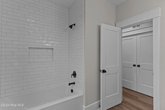 bathroom with baseboards, visible vents, shower / washtub combination, and wood finished floors