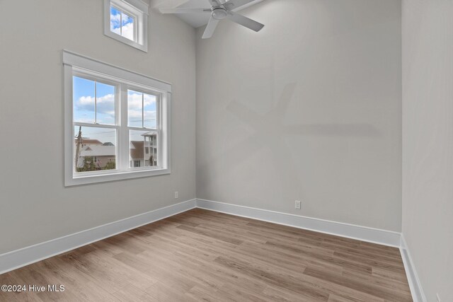 spare room featuring a ceiling fan, light wood finished floors, and baseboards