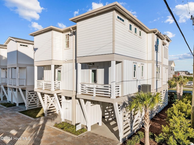 back of property with board and batten siding, central AC, and stairway