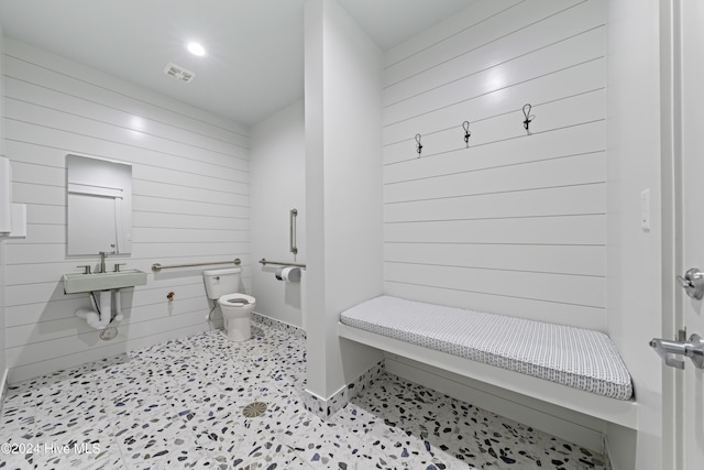 bathroom with visible vents, wood walls, and toilet