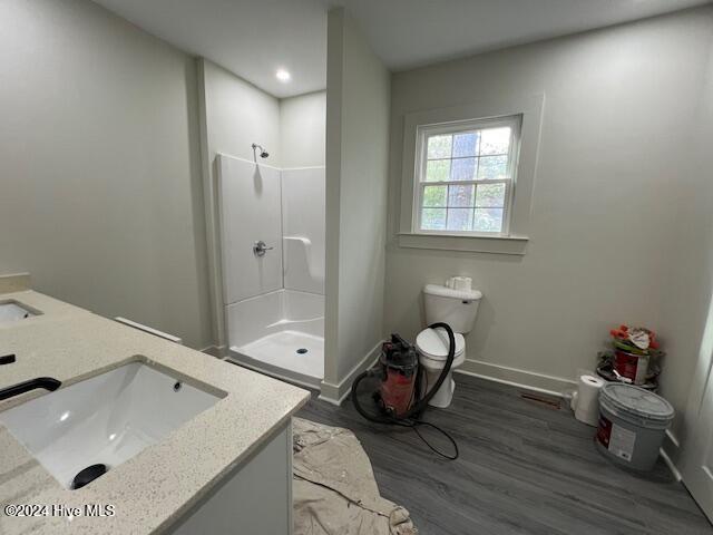 bathroom with a shower, hardwood / wood-style floors, vanity, and toilet