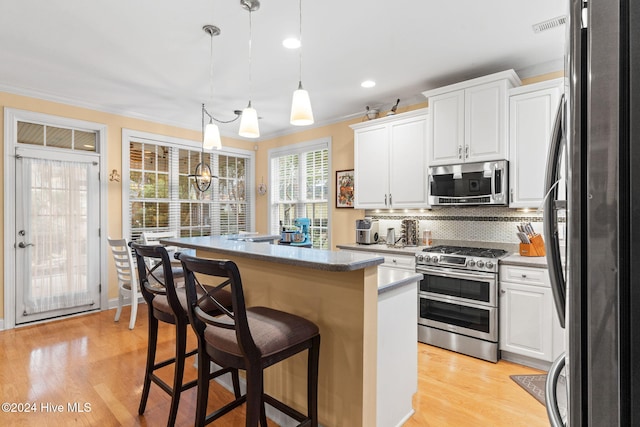 4151 Windham Ln, Southport, NC 28461 - kitchen with appliances with stainless steel finishes, a kitchen island, white cabinets, crown molding, and tasteful backsplash