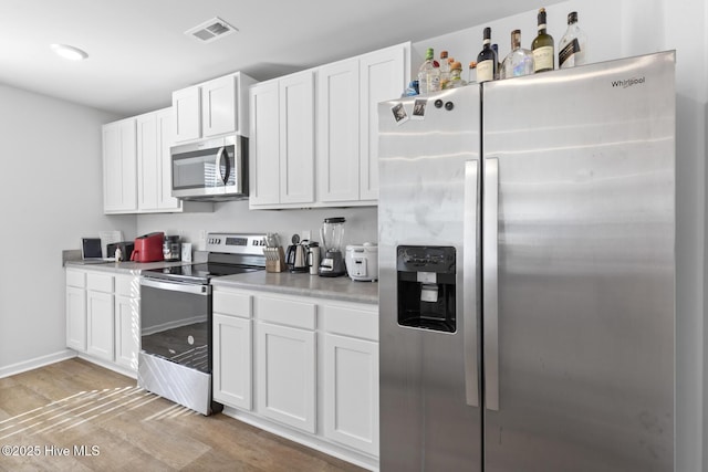 kitchen featuring light hardwood / wood-style flooring, white cabinets, and appliances with stainless steel finishes