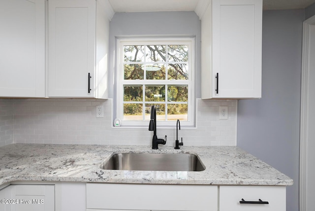 kitchen with white cabinetry, sink, tasteful backsplash, and light stone countertops