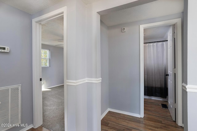 hall featuring a textured ceiling and dark hardwood / wood-style floors