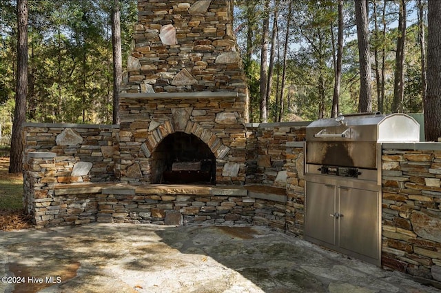 view of patio / terrace featuring an outdoor stone fireplace, area for grilling, and a grill