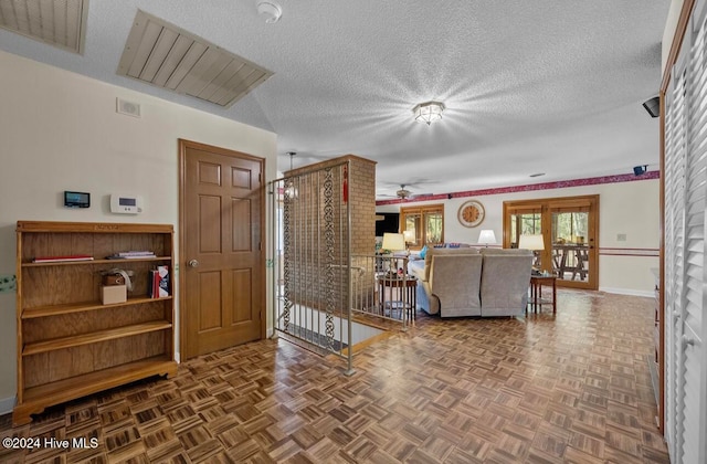 living room with ceiling fan, a textured ceiling, and parquet flooring