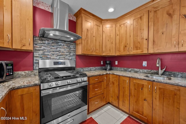 kitchen featuring appliances with stainless steel finishes, dark stone counters, sink, wall chimney range hood, and light tile patterned flooring