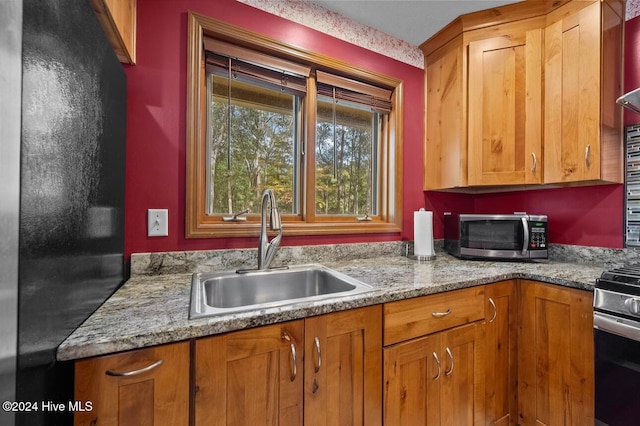 kitchen with tasteful backsplash, stone counters, sink, and appliances with stainless steel finishes