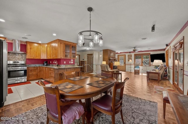 dining room with ceiling fan with notable chandelier, sink, a textured ceiling, and light parquet floors