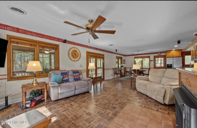 living room featuring ceiling fan, crown molding, and light parquet flooring