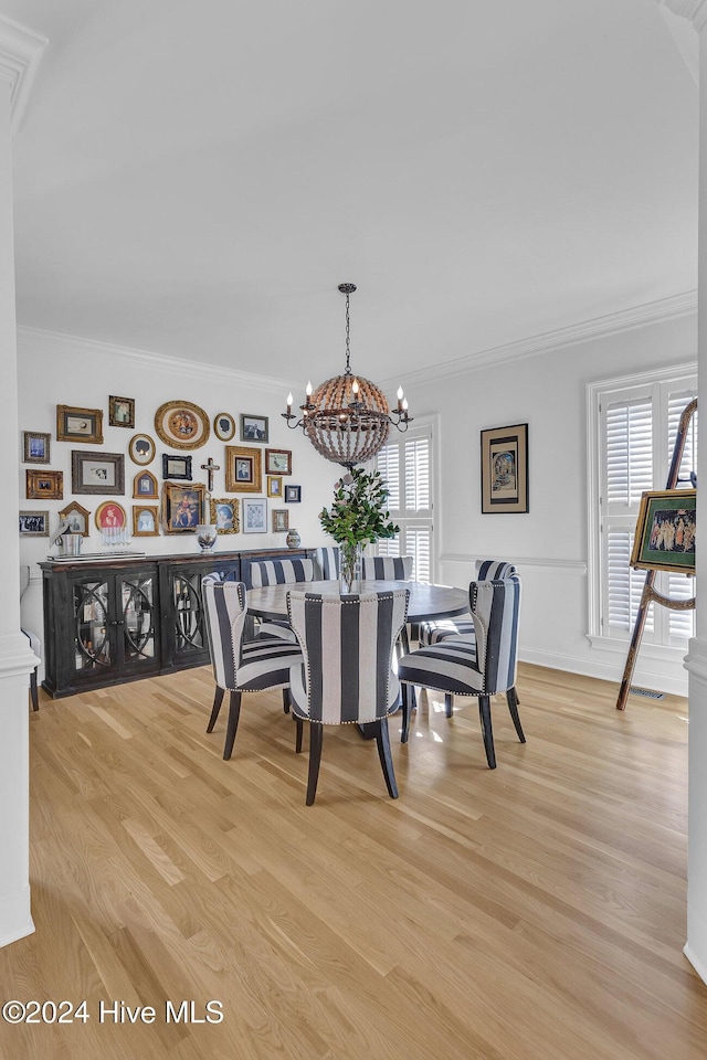 dining space featuring light wood-type flooring, crown molding, and a chandelier