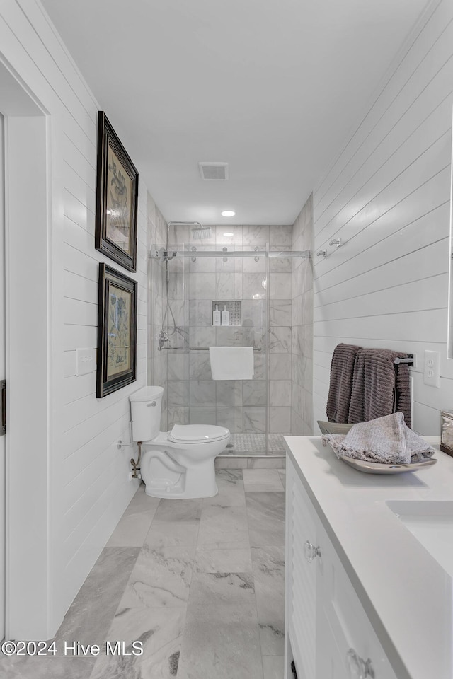 bathroom featuring toilet, wood walls, an enclosed shower, and vanity