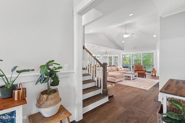 stairway featuring crown molding, ceiling fan with notable chandelier, vaulted ceiling, and hardwood / wood-style flooring