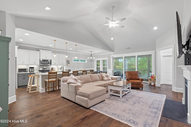 living room featuring ceiling fan with notable chandelier, high vaulted ceiling, dark wood-type flooring, and sink