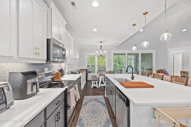 kitchen featuring pendant lighting, white cabinetry, stainless steel appliances, and a kitchen island with sink