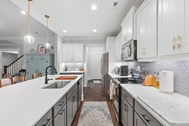 kitchen featuring sink, dark wood-type flooring, stainless steel appliances, pendant lighting, and white cabinets