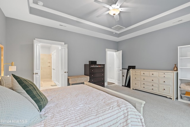 carpeted bedroom featuring ceiling fan, ensuite bath, and a tray ceiling