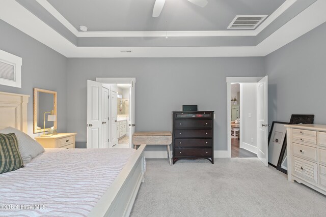 carpeted bedroom with a tray ceiling, ceiling fan, and ensuite bathroom