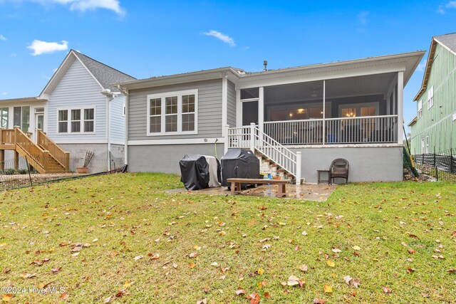 back of property with a sunroom, a yard, and a patio