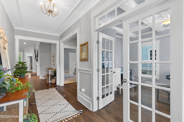 hallway with crown molding, dark hardwood / wood-style flooring, and a notable chandelier