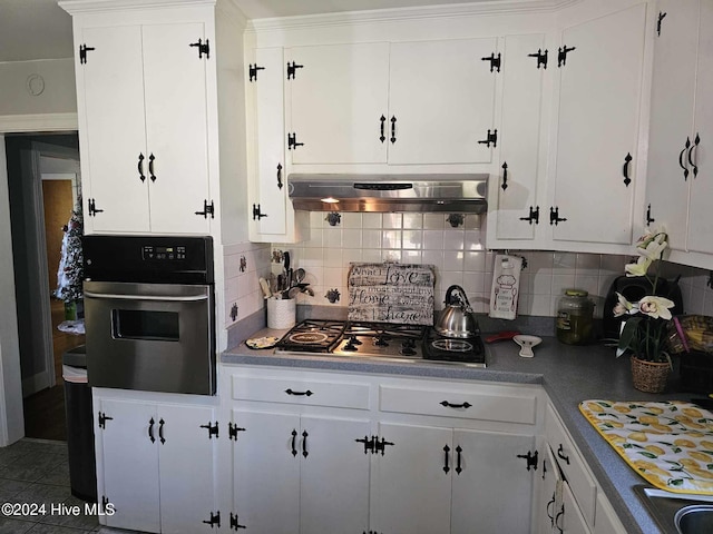 kitchen with white cabinets, tasteful backsplash, appliances with stainless steel finishes, and exhaust hood