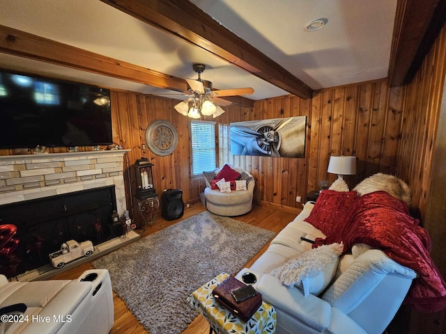 living room with a fireplace, beam ceiling, wood walls, hardwood / wood-style floors, and ceiling fan