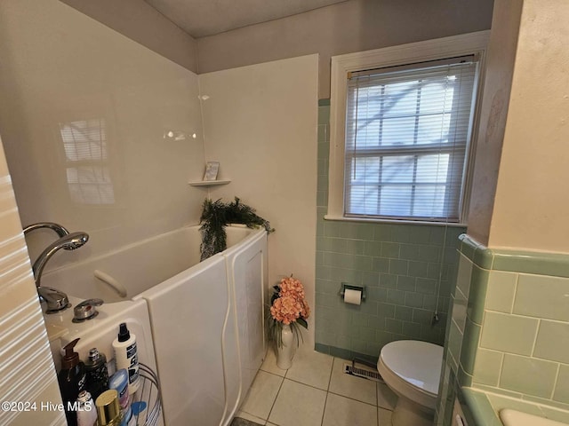 bathroom featuring toilet, tile walls, a bathtub, and tile patterned floors