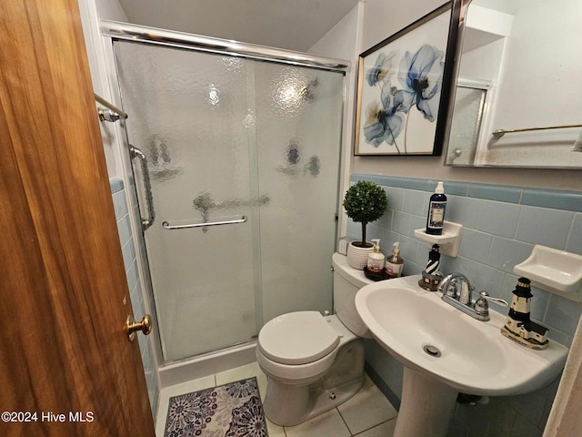 bathroom featuring toilet, tile patterned floors, tile walls, sink, and an enclosed shower