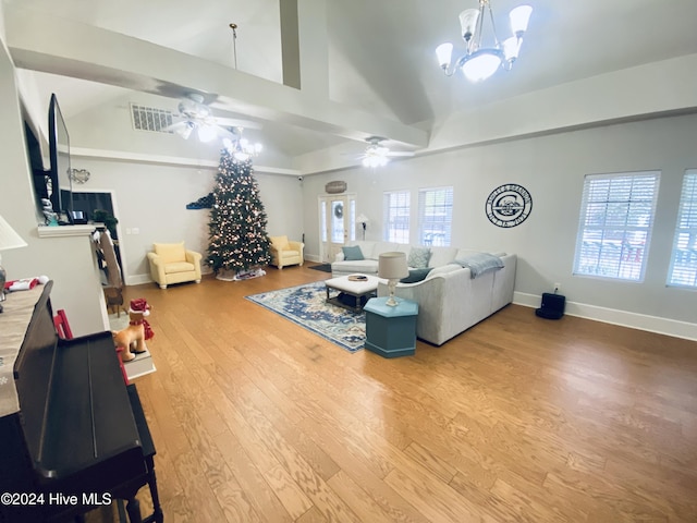 living room with ceiling fan with notable chandelier, a healthy amount of sunlight, vaulted ceiling, and wood-type flooring